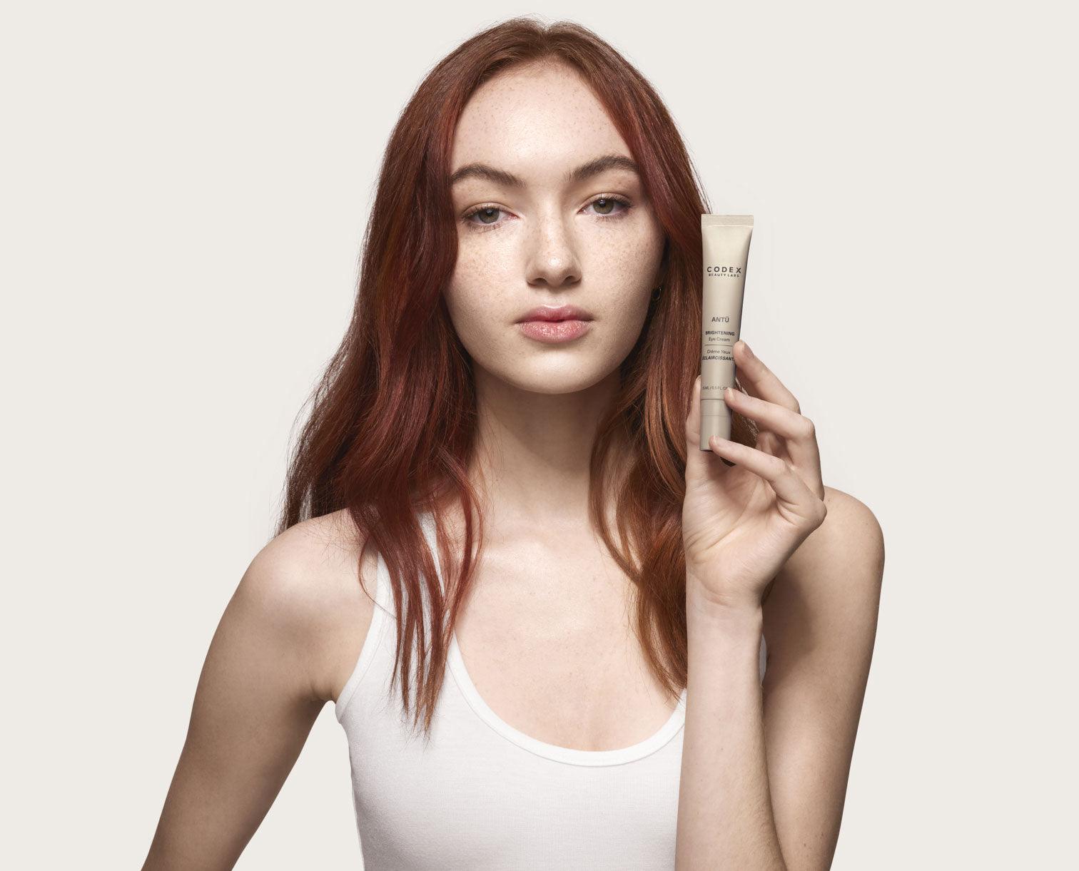 Image of female Codex Beauty Labs model holding an Antu Moisturizer next to her face